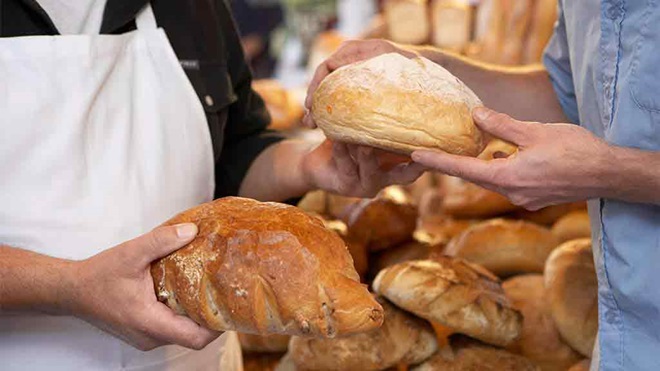two people exchanging loaves of bread